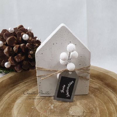 Handgemachtes Haus aus Beton, dekoriert mit Weihnachtsblumen